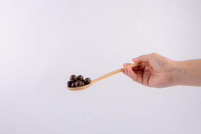 Close-up of hand holding key against white background