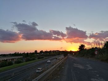 Road by city against sky during sunset