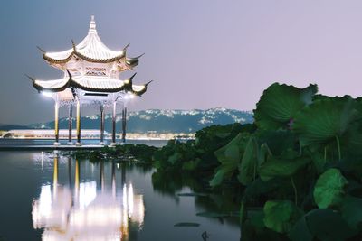 Traditional building by lake against clear sky