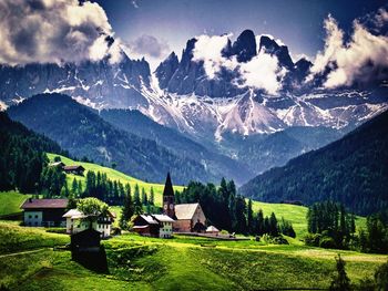 Houses on field by mountain against sky