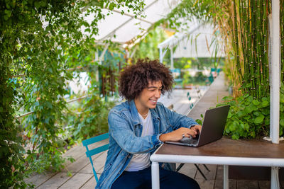 Young woman using laptop while sitting on chair