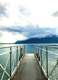 Pier on sea against cloudy sky