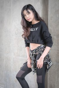 Beautiful young woman standing against wall