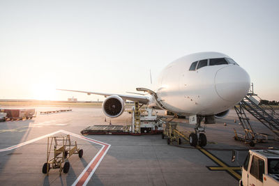 Airplane on runway against clear sky during sunset