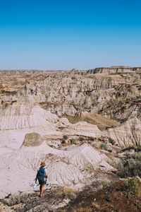 Rear view of man walking on mountain against blue sky