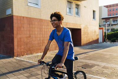 Smiling man riding bicycle in city at sunset