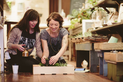 Female coworkers planting plants in crate at garden center