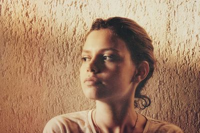 Young woman looking away against wall