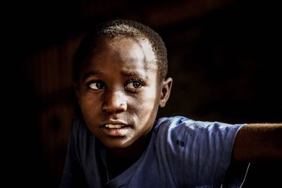 Close-up portrait of young man against black background