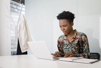 Young businesswoman with diary using laptop at desk in office