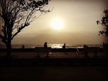 Silhouette people on beach against sky during sunset