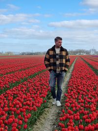 Man standing by flowers on field against sky