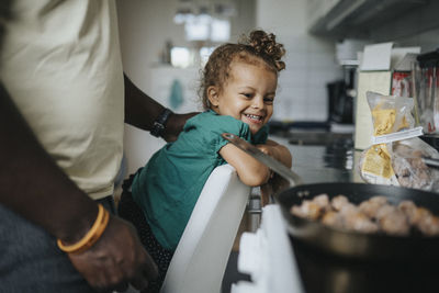 Happy girl looking at meal being cooked by father