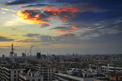 Cityscape against cloudy sky at sunset