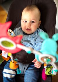 Cute little baby sitting in his rocking chair with toys