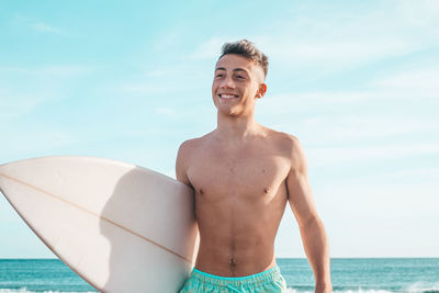 Portrait of shirtless man standing against sea