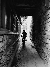Silhouette boy riding bicycle at alley
