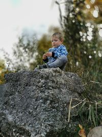 Boy on rock against trees