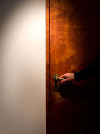 Close-up of hand holding wooden door