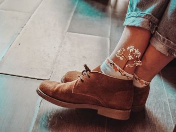 Low section of woman with flower in sock on hardwood floor