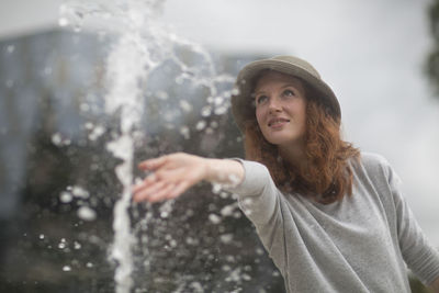 Young woman with hat outside playing with a fountain
