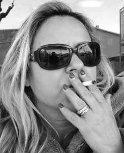 Close-up of woman wearing sunglasses smoking cigarette