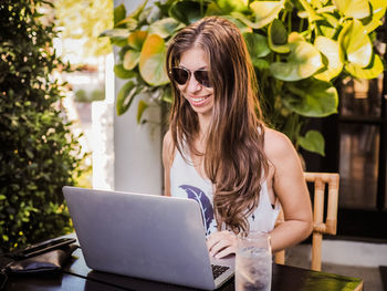 Portrait of young woman using phone while sitting on table