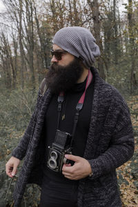Midsection of man holding camera standing outdoors