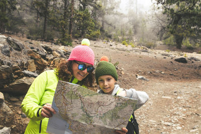 Woman with son reading map at forest
