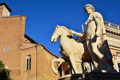 Low angle view of statue against historic building against clear sky