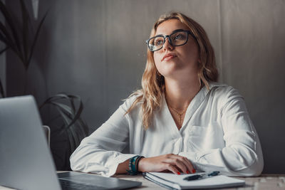 Young woman using mobile phone while sitting in office