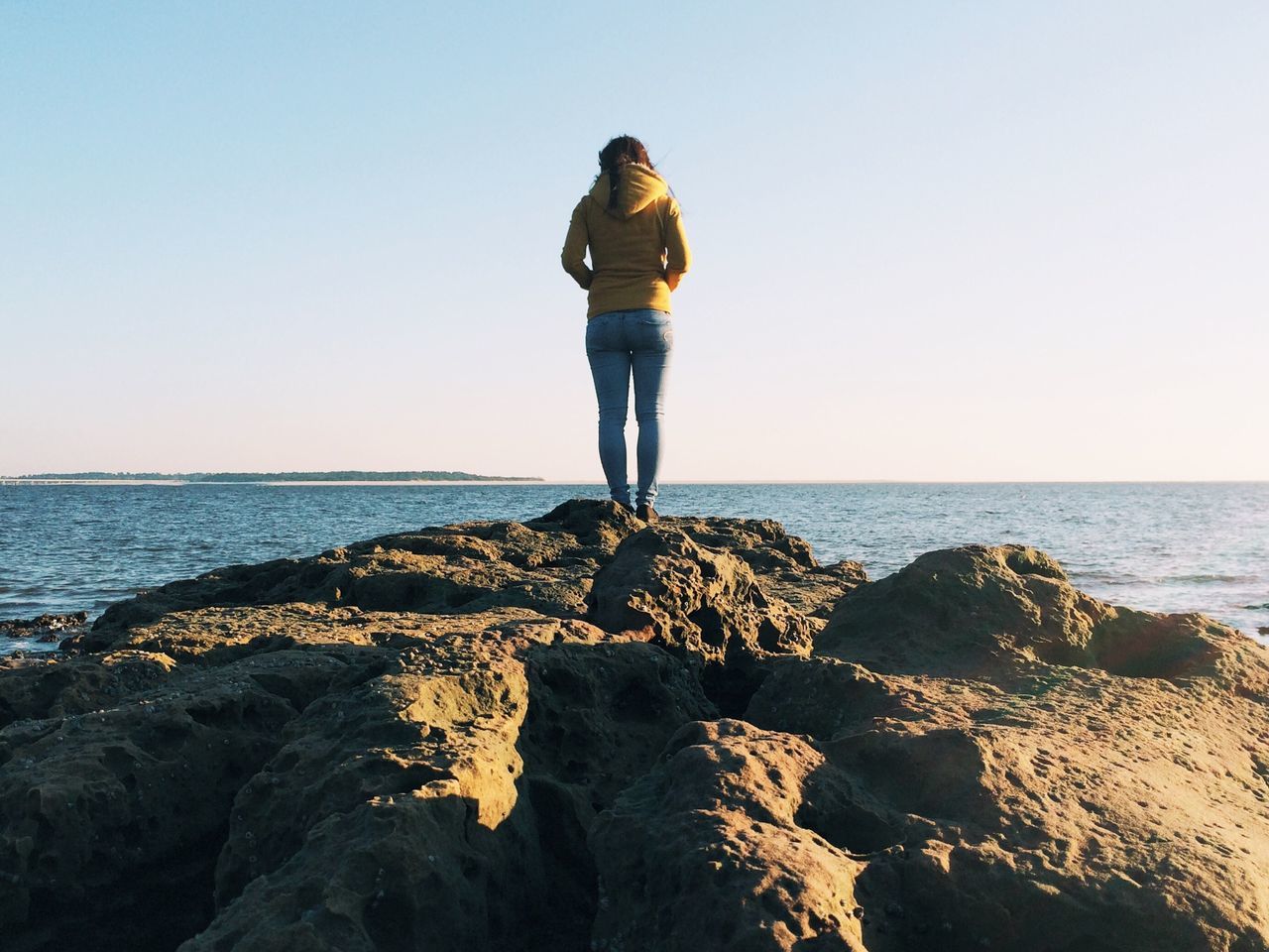 sea, horizon over water, clear sky, full length, water, lifestyles, rear view, standing, leisure activity, beach, copy space, tranquil scene, tranquility, shore, beauty in nature, scenics, casual clothing, rock - object