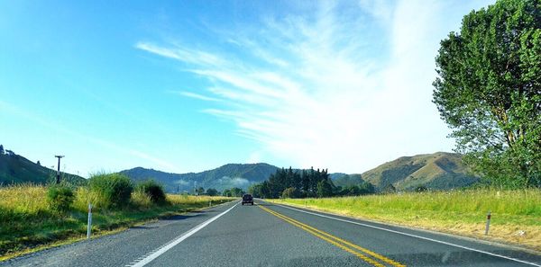 Road by trees against blue sky