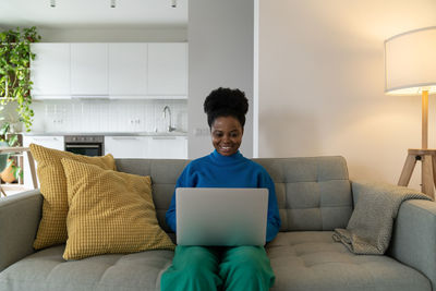 Successful african american woman freelancer smiling working from home doing order using laptop