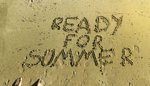 Low section of person standing by text on sand