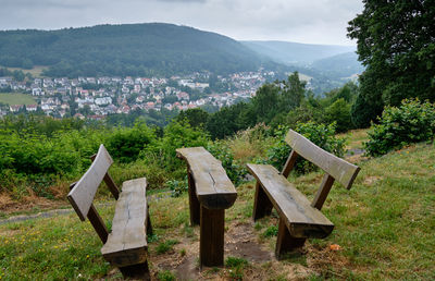 Empty bench on field by mountains against sky