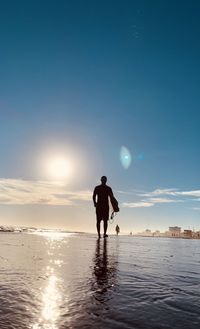 Rear view of silhouette man on beach against sky during sunset