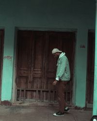 Side view of man standing by door of building