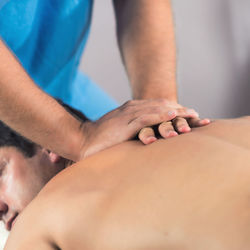 Man receiving massage therapy while lying on bed