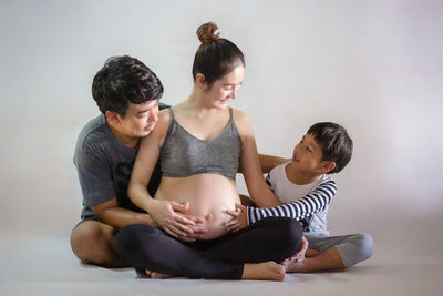 Friends sitting on floor against white background