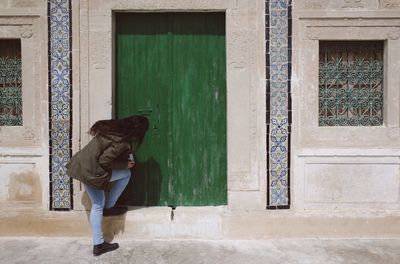 Full length of woman standing against door of building