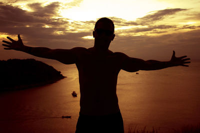 Man with outstreched arms at sunset