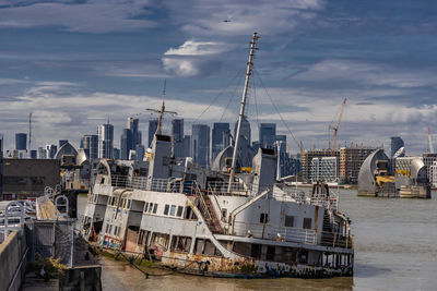 Sailboats in harbor by city against sky