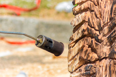 Close-up of blow torch by wooden sculpture