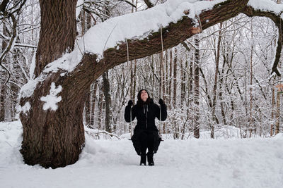 A woman on a swing in a snowy forest