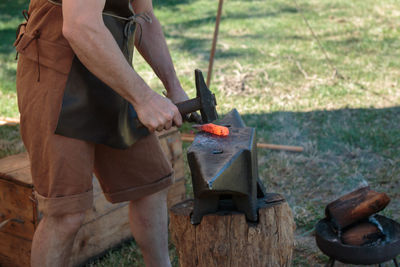 Midsection of blacksmith shaping metal