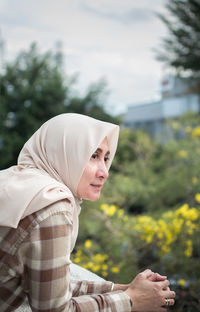 Side view of young woman against plants