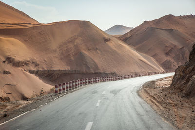 Empty road amidst desert against sky