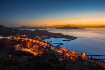 High angle view of illuminated sea against sky at dusk