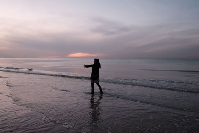 Silhouette man standing on beach against sky during sunset